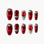 Red press-on nails set with silver rhinestones and large red gem accents on a white background.