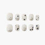 White press-on nails with silver glitter, black heart accents, and metallic embellishments