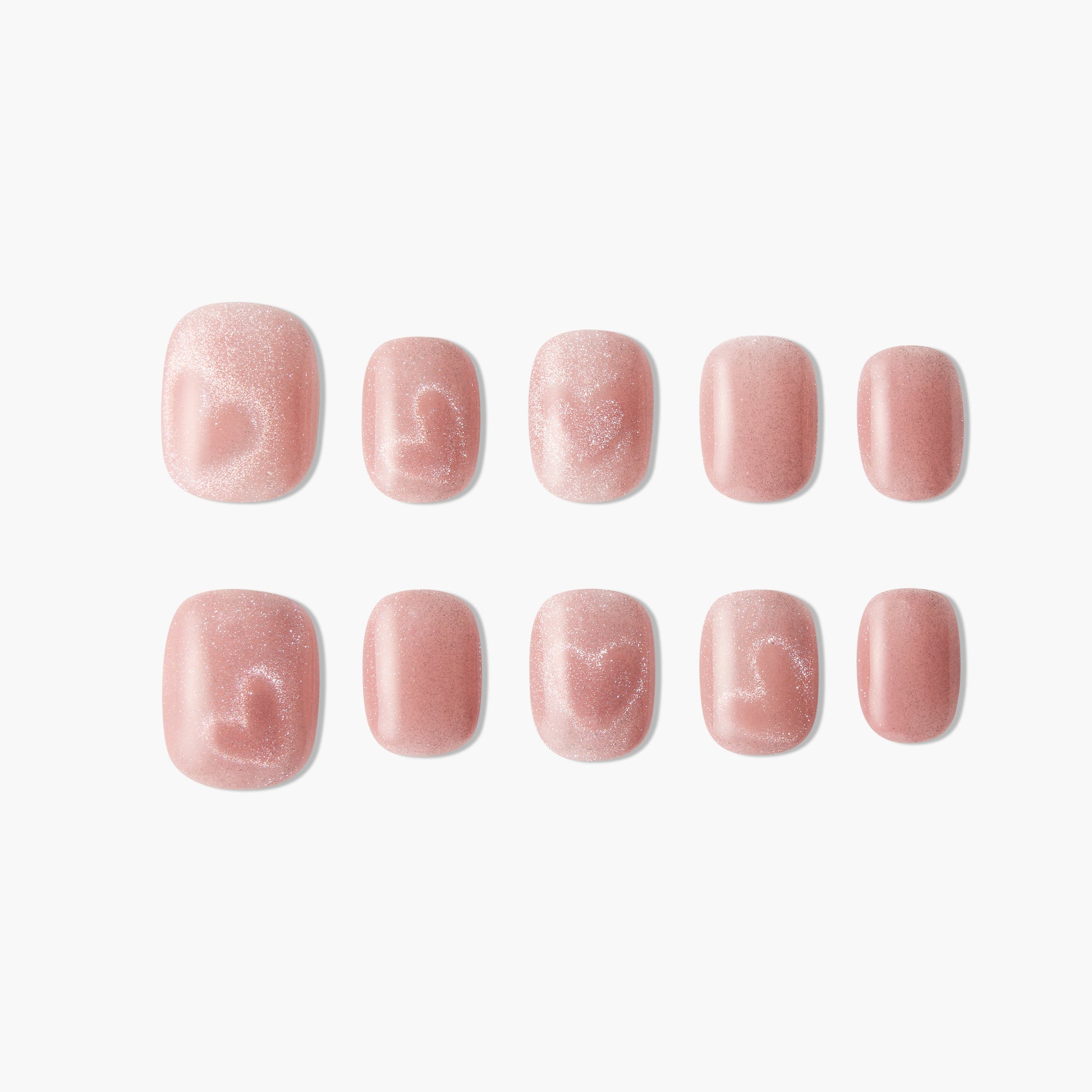 Pink glitter press-on nails with subtle heart designs arranged on a white background.