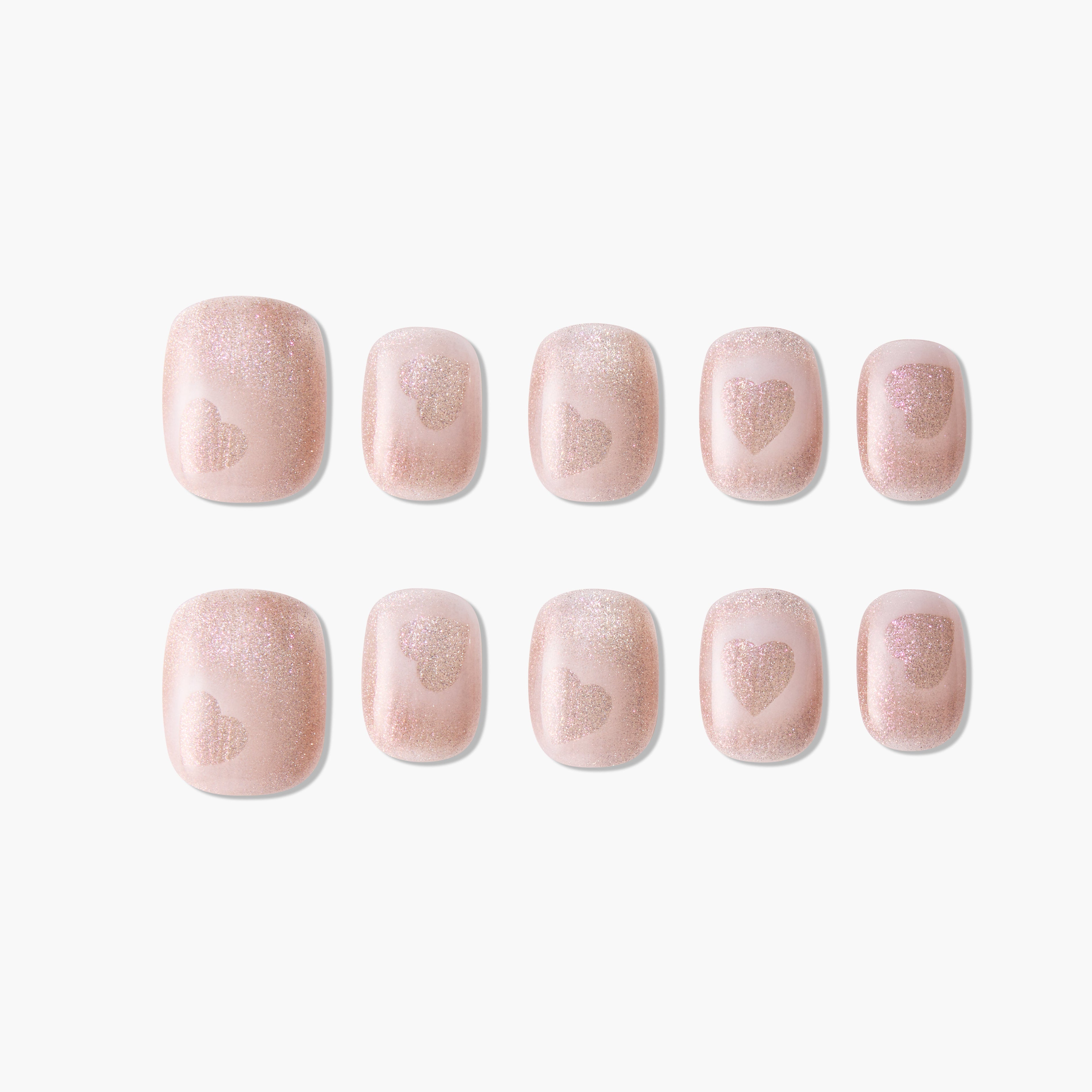 Set of pink glitter press-on nails with heart design, short square shape, on white background.