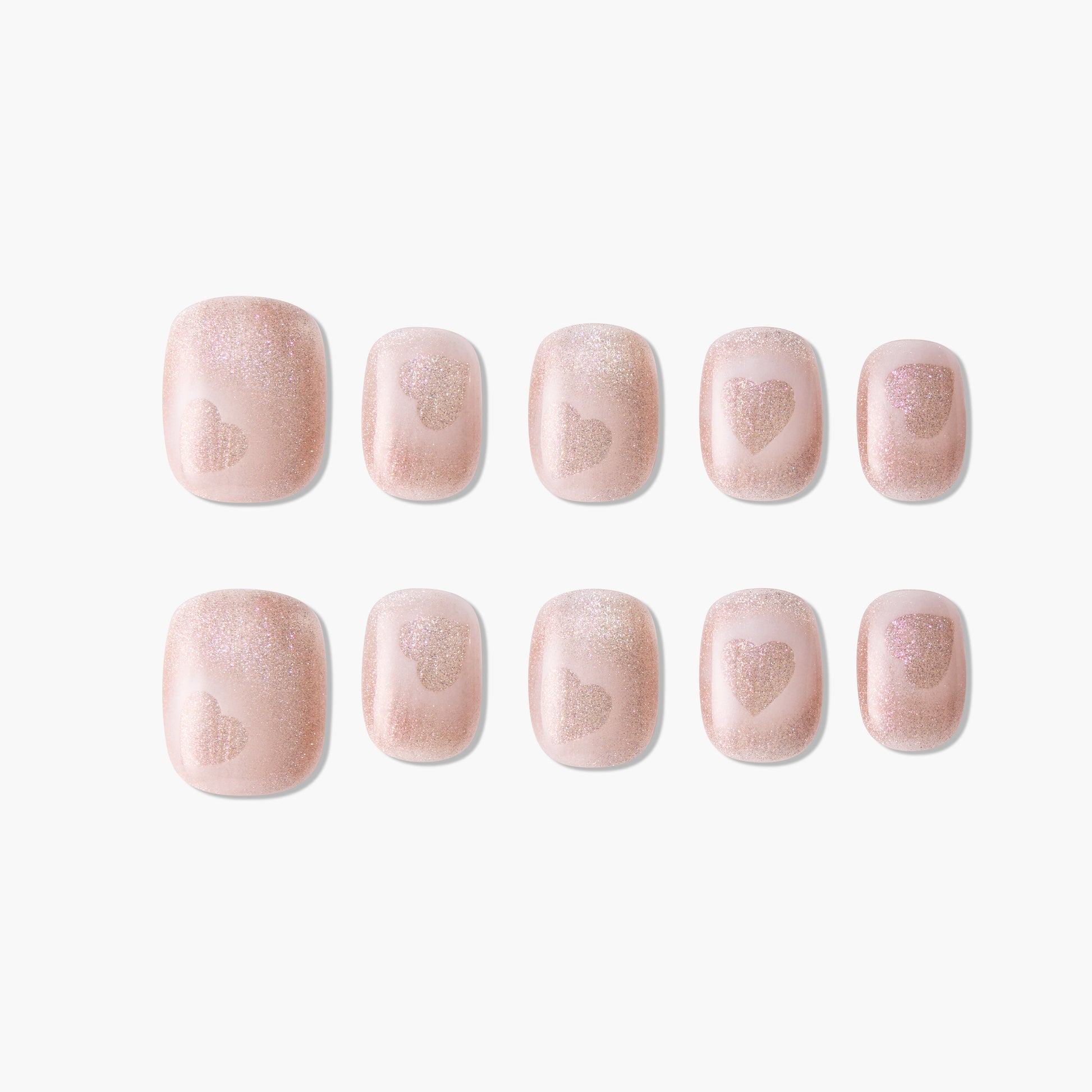 Set of pink glitter press-on nails with heart design, short square shape, on white background.