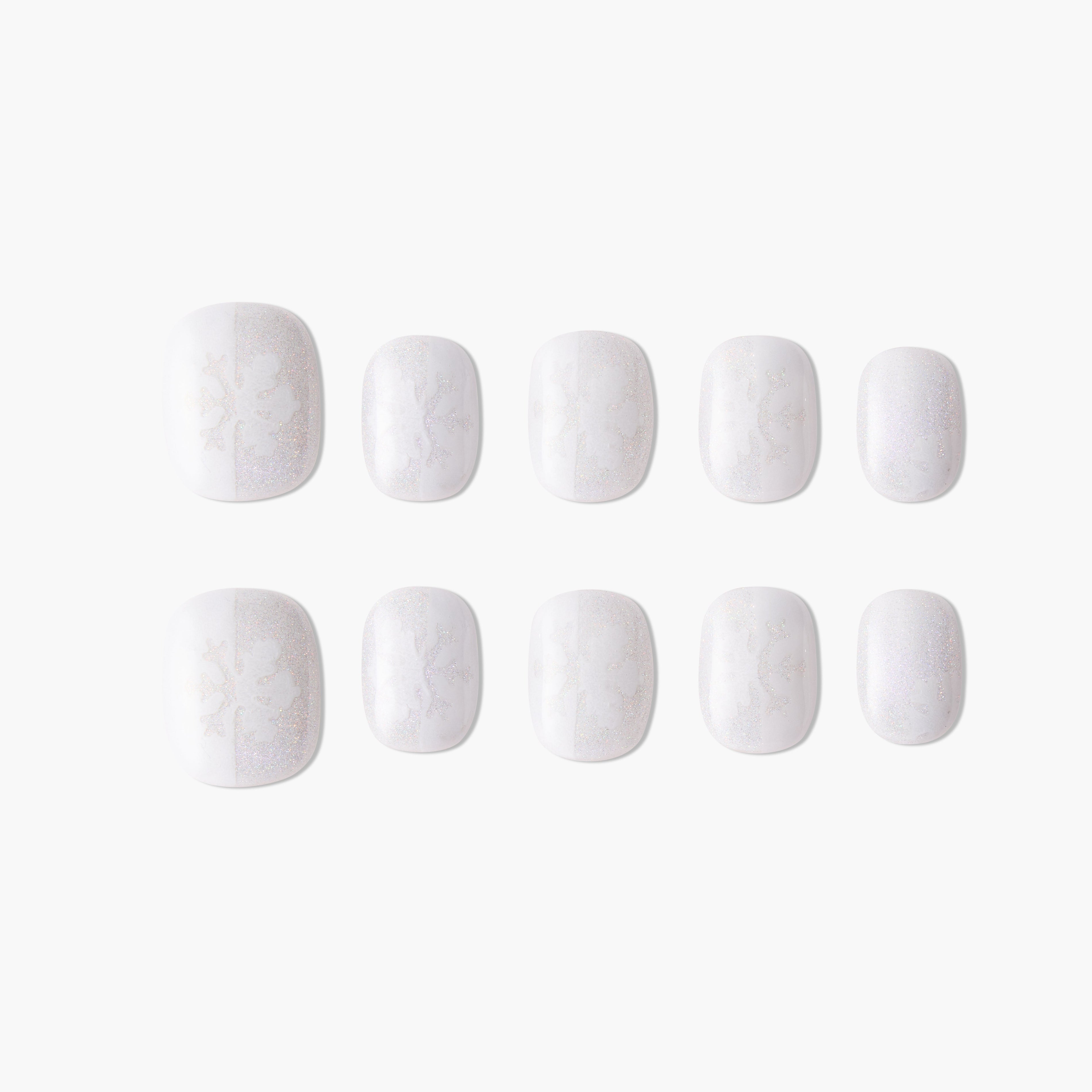 Handmade white press-on nails with subtle snowflake and glitter design on plain background