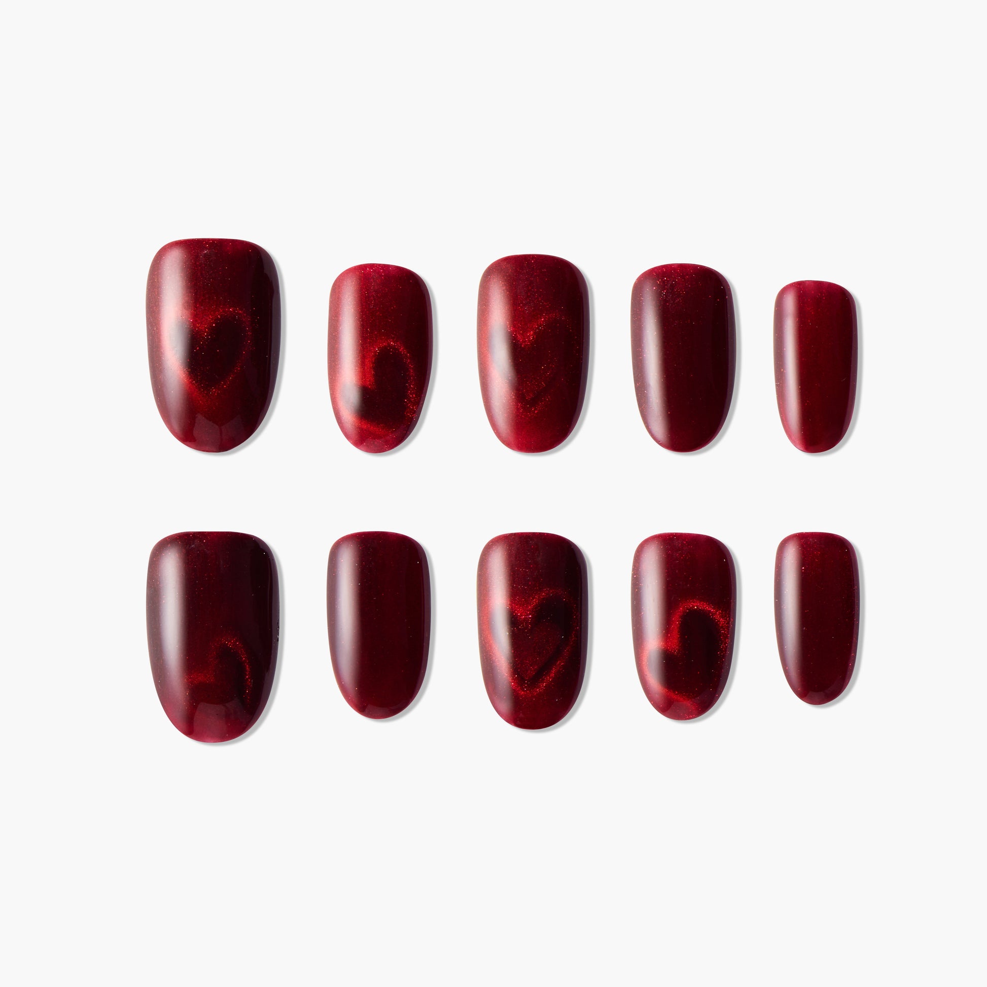 Handmade red press-on nails with glossy finish and subtle heart designs, reusable manicure