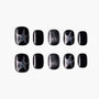 Black press-on nails with silver glitter star and shimmer designs, arranged on white background
