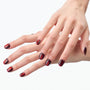 Hand with glossy red and black ombre press-on nails, close-up on white background