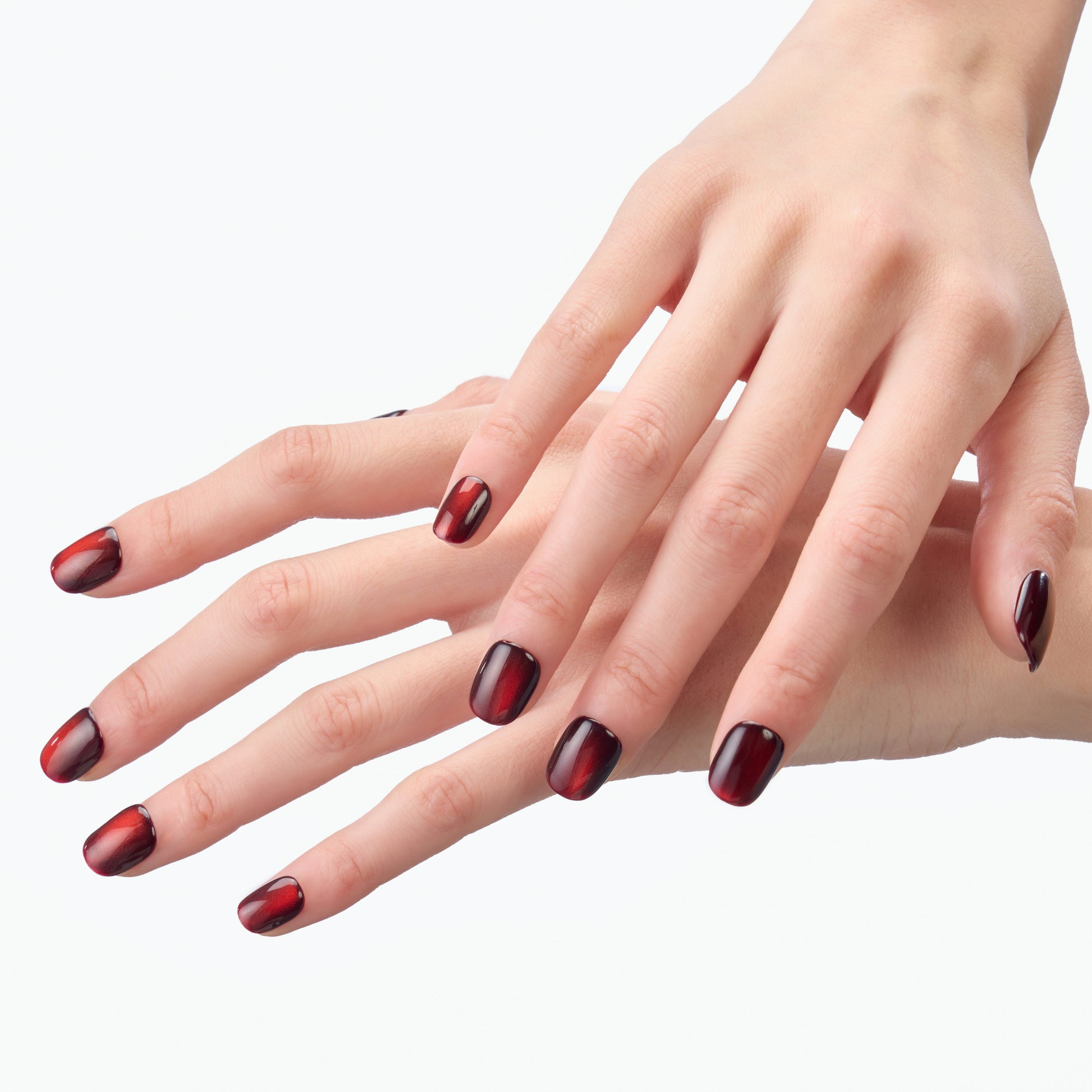 Hand with glossy red and black ombre press-on nails, close-up on white background