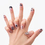 Hand with reusable press-on nails in black and nude, featuring 3D stars, flowers, and pearls.