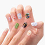 Hand with colorful handmade press-on nails featuring unique 3D art and glitter designs