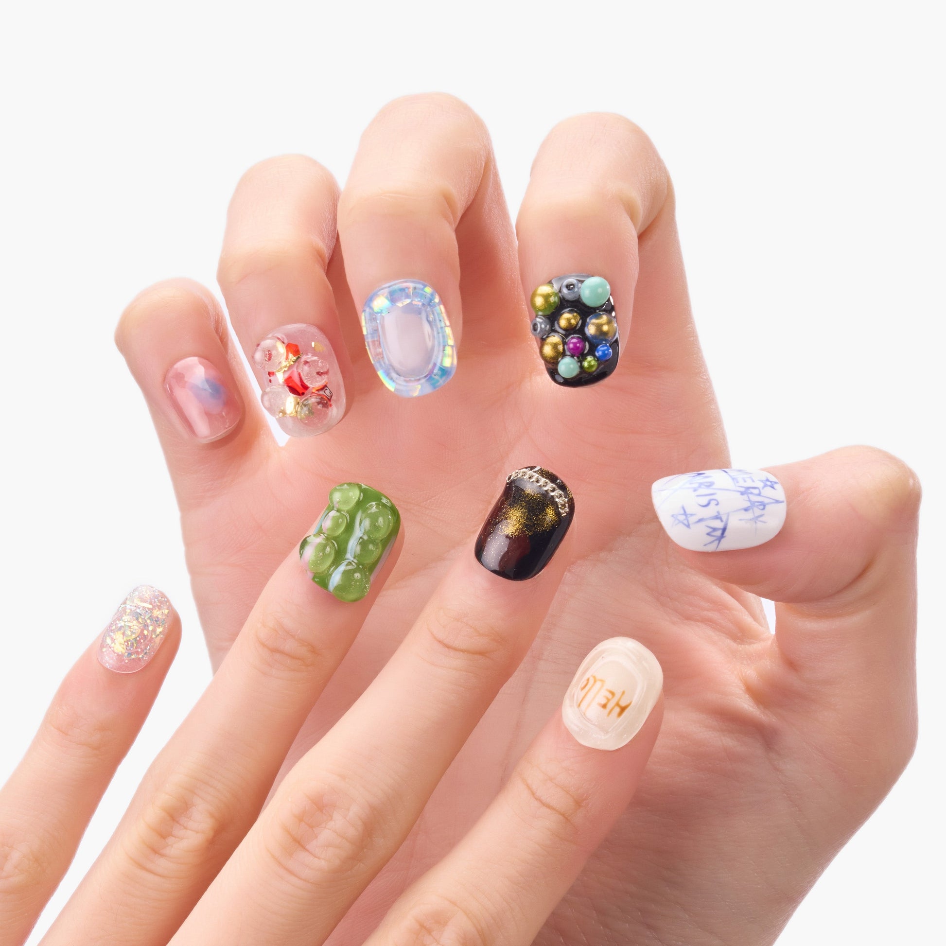 Hand with colorful handmade press-on nails featuring unique 3D art and glitter designs