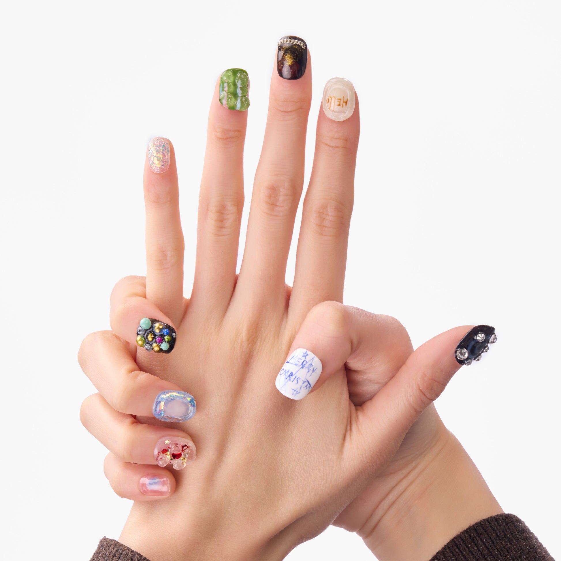 Hands displaying colorful handmade press-on nails with 3D gems and artistic designs