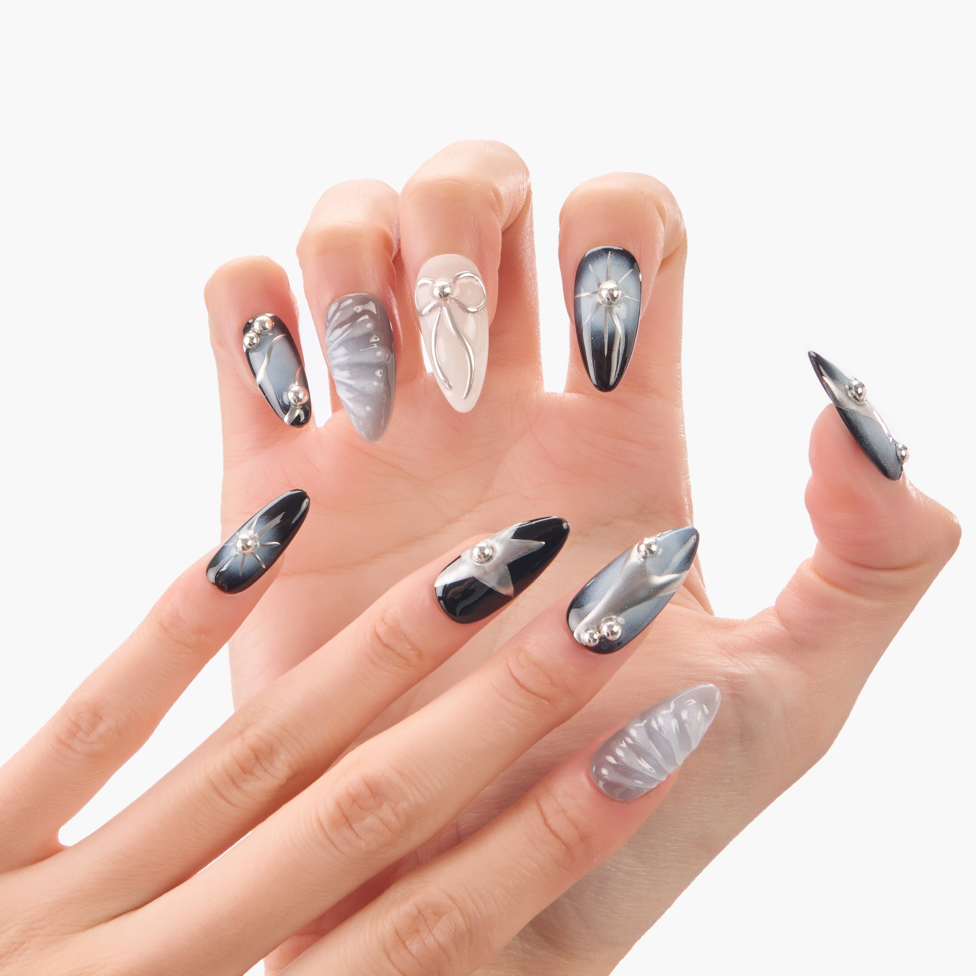 Hand with long stiletto press-on nails in metallic silver and black, 3D bows and rhinestones