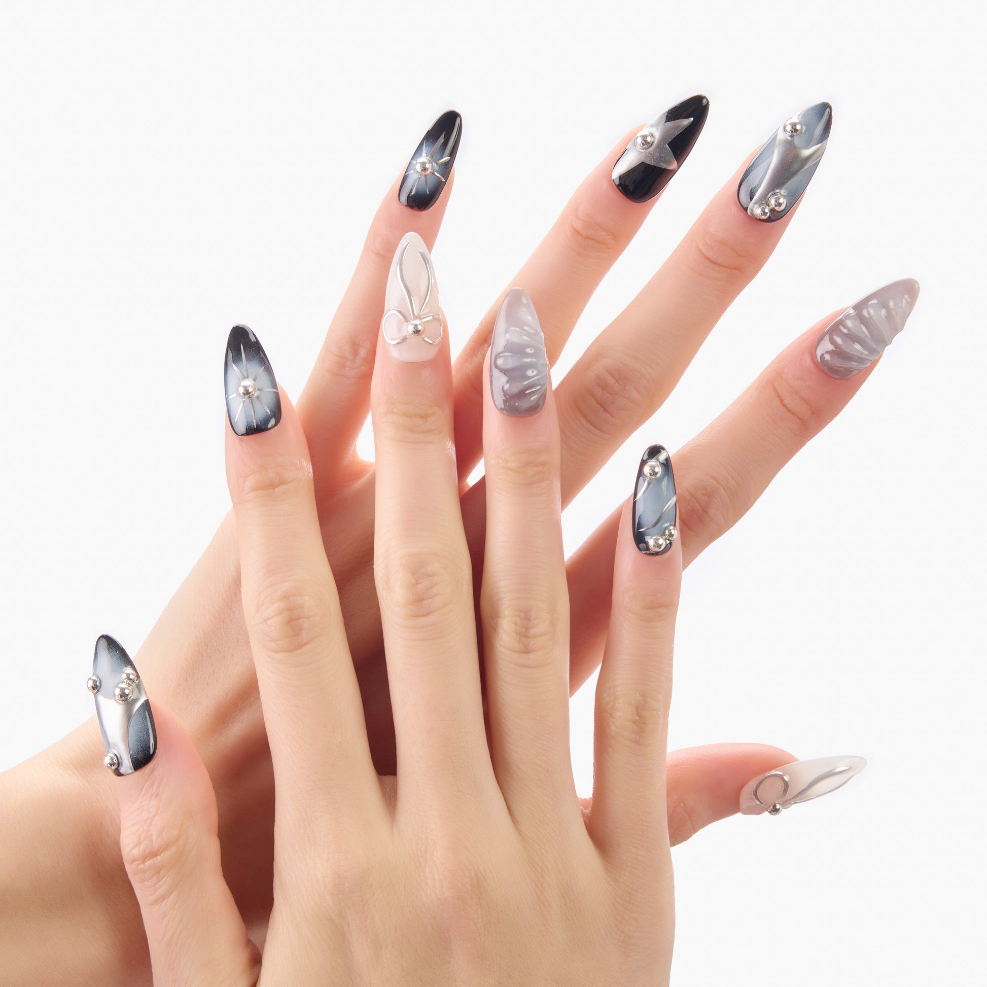 Hand with long stiletto press-on nails in black, silver, and gray marble designs with 3D accents