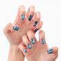 Hands with dark blue press-on nails featuring star and sparkle designs, close-up