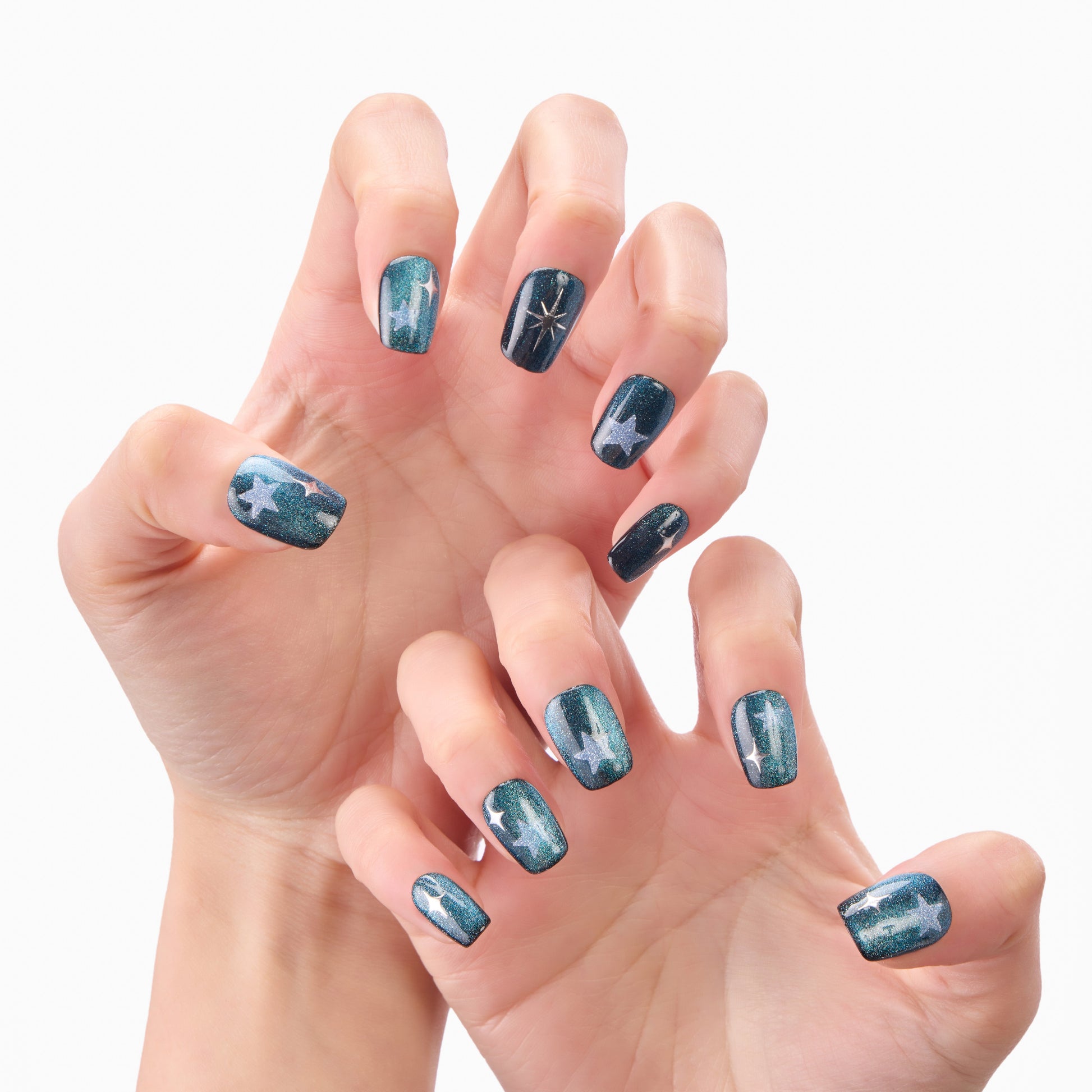 Hands with dark blue press-on nails featuring star and sparkle designs, close-up