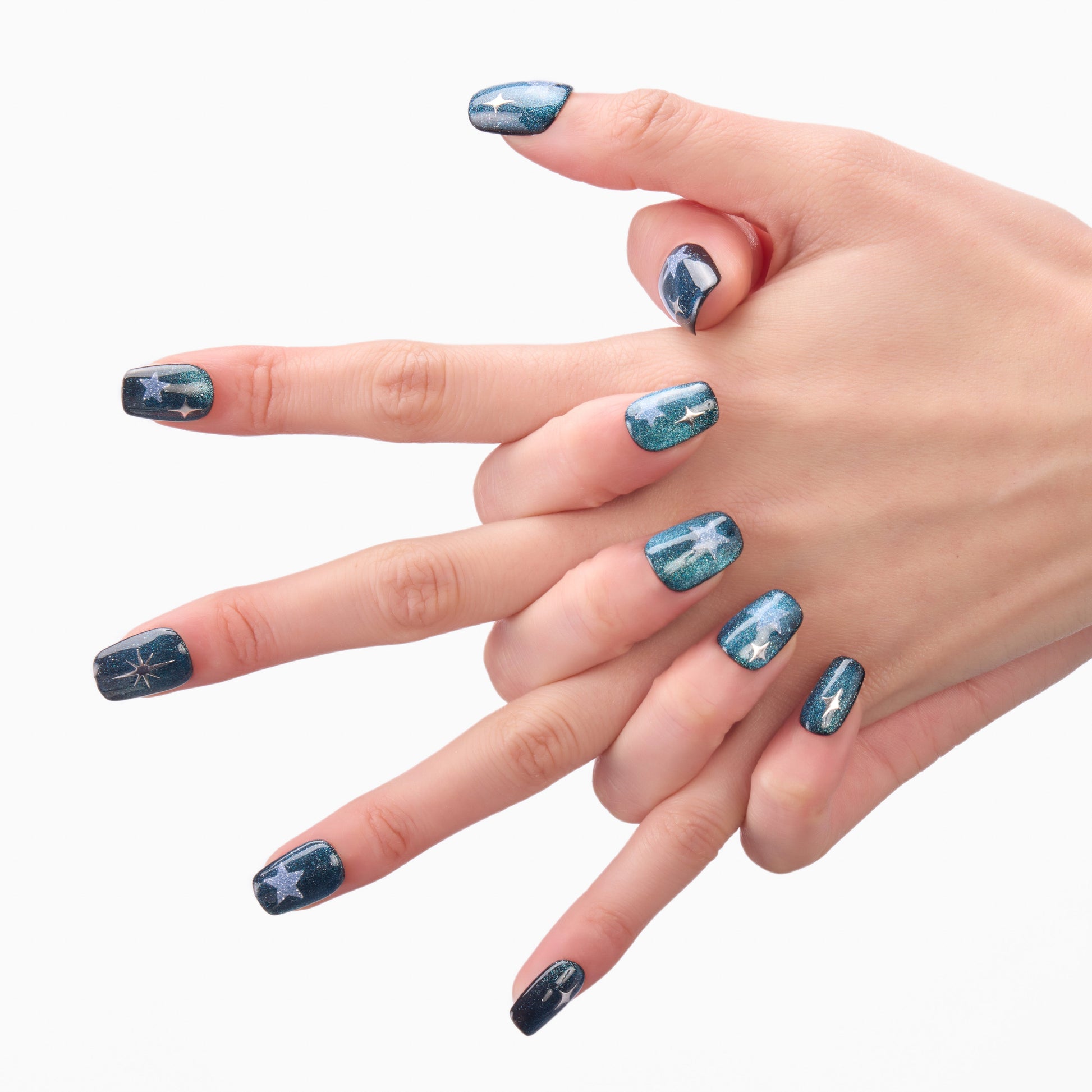Hand with blue press-on nails featuring silver star and constellation designs