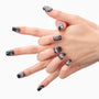 Hand with black metallic press-on nails featuring rhinestone and glitter accents