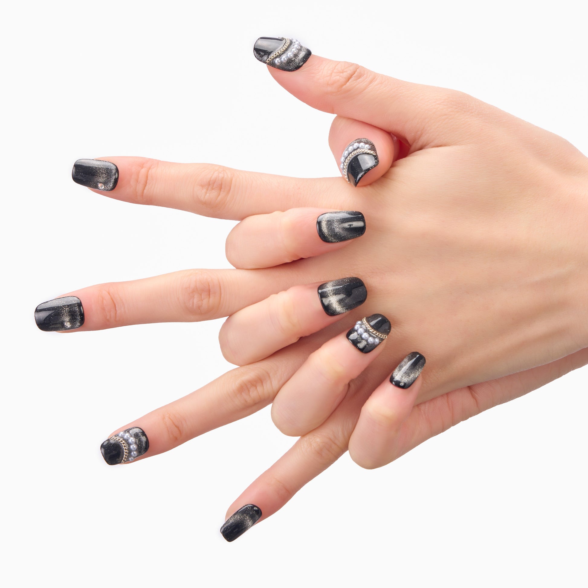 Hand with black metallic press-on nails featuring rhinestone and glitter accents