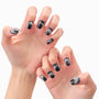 Hands with black and silver press-on nails featuring rhinestone and metallic accents