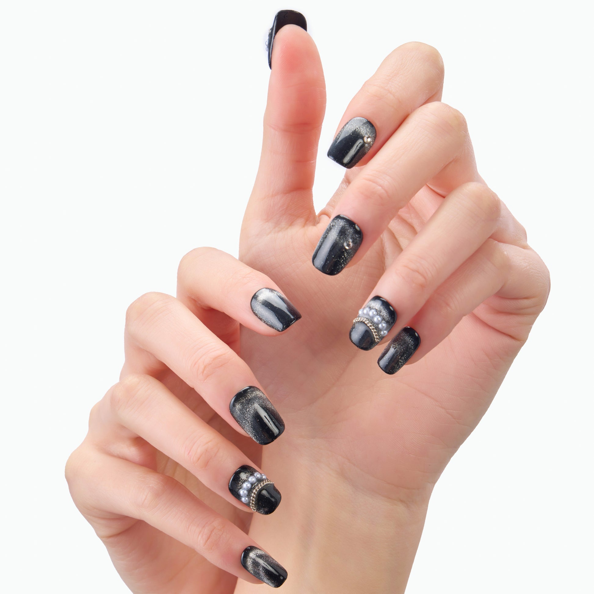 Hand with glossy black press-on nails featuring silver glitter and rhinestone accents.