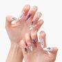 Handmade press-on nails featuring long almond shape, purple chrome, marble accents, and star charms