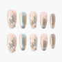 Iridescent press-on nails with pearl and gem accents, featuring delicate floral designs.