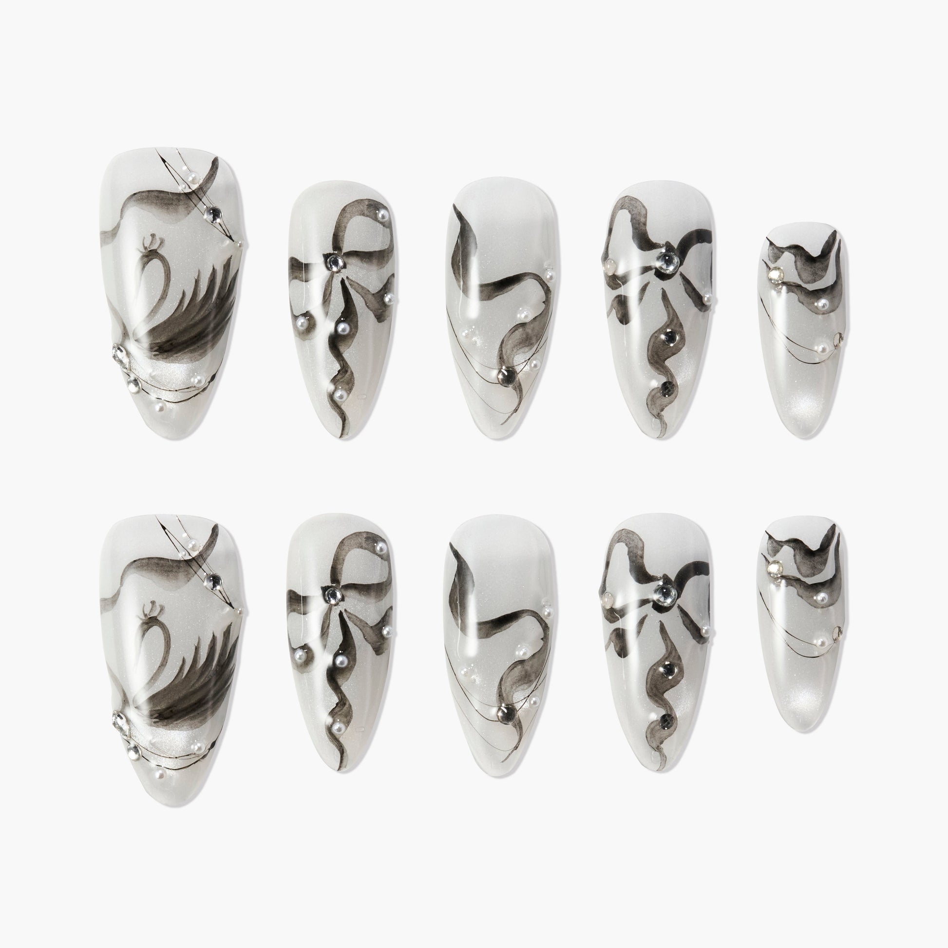 Handmade press-on nails with black abstract designs and pearl accents on a white base.