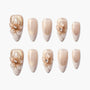 Set of gold and nude press-on nails with 3D floral designs and pearl accents, salon-style finish