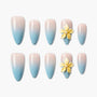 Blue and nude ombre press-on nails with 3D yellow flower accents, displayed on white background.