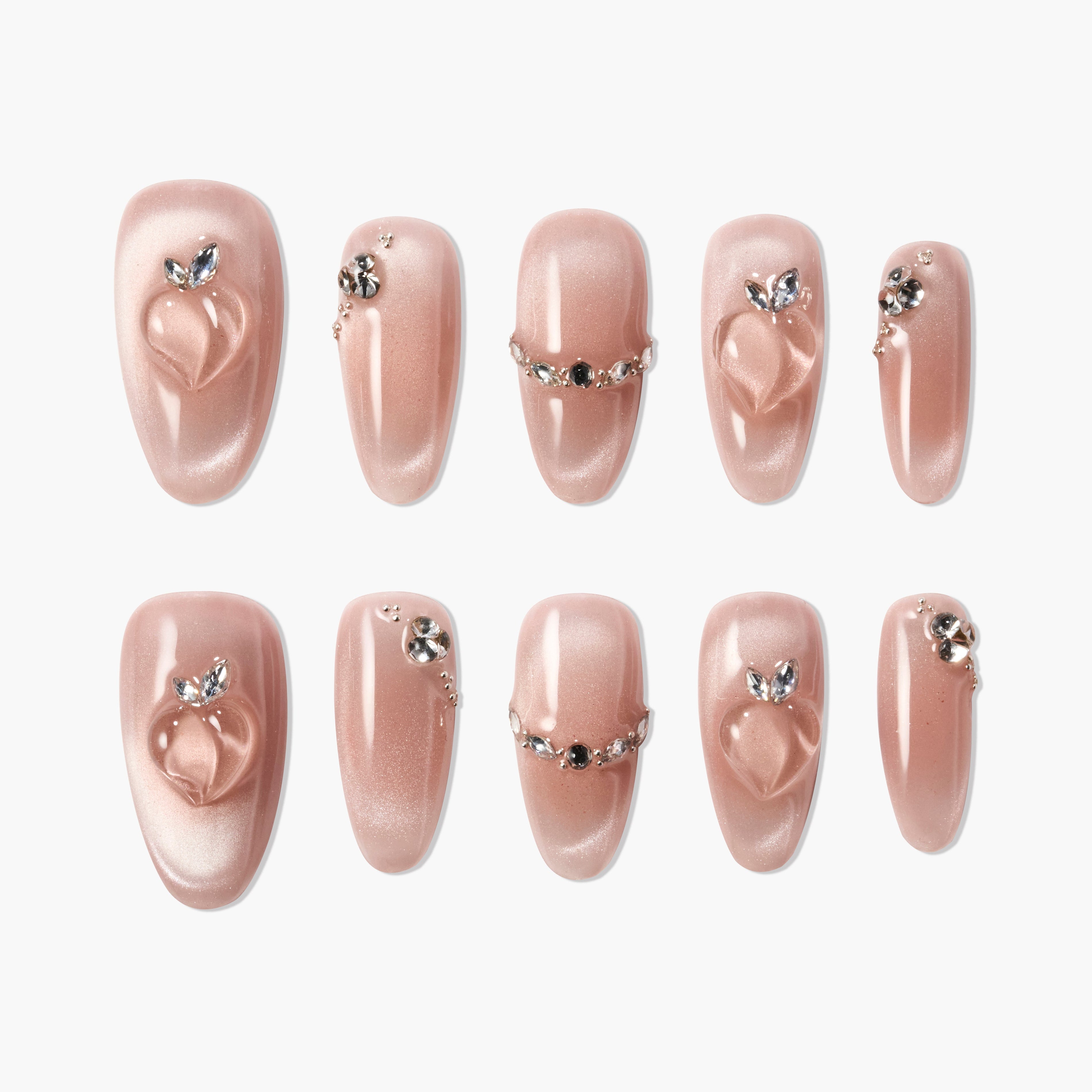Shimmery nude press-on nails with peach accents and rhinestone embellishments