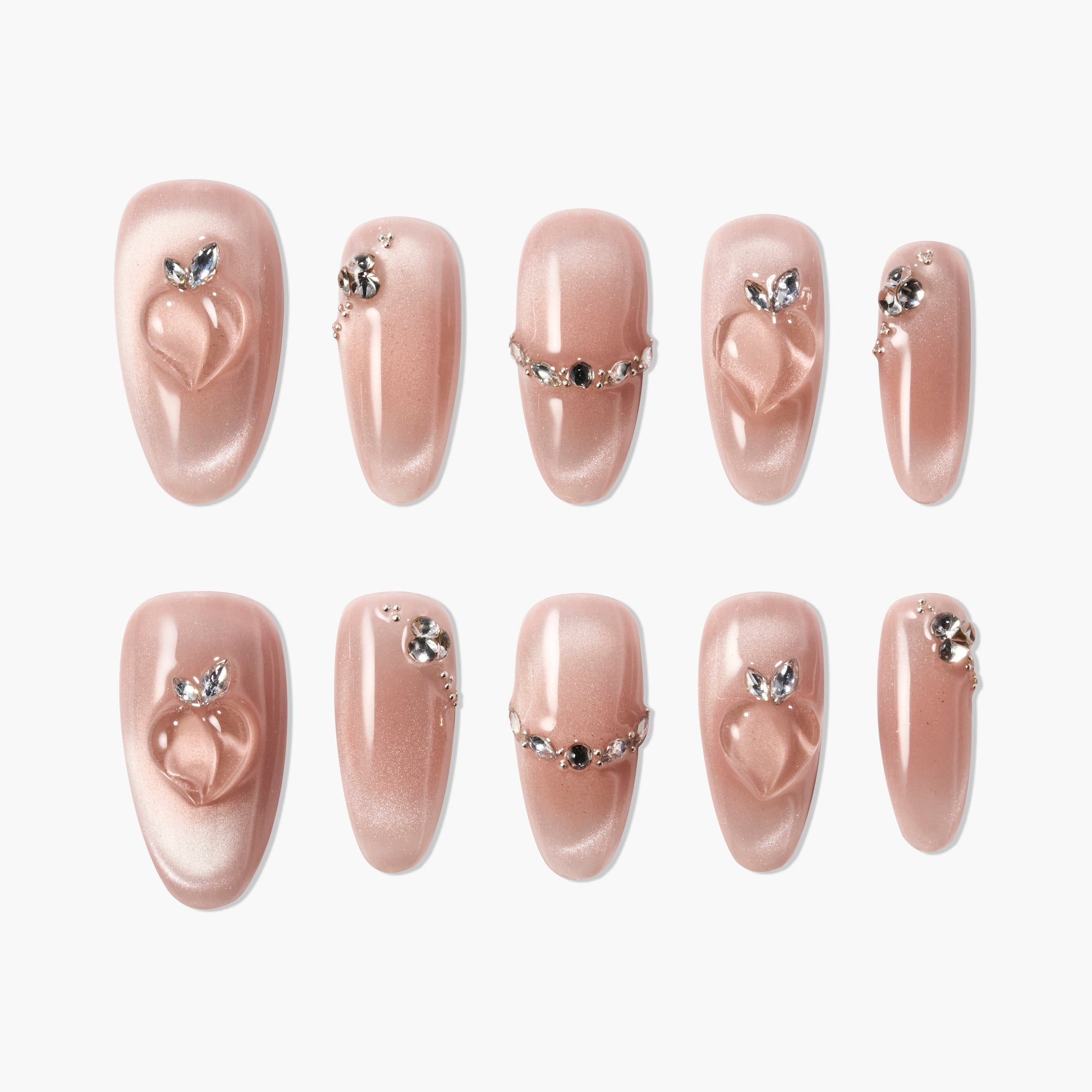 Shimmery nude press-on nails with peach accents and rhinestone embellishments