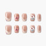 Handmade press-on nails in nude pink with 3D bow, cupcake, and confetti designs.