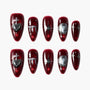 Glossy dark red press-on nails with silver heart, star, planet, and drip designs.