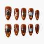 Set of glossy brown press-on nails with black heart, glitter, and abstract star designs