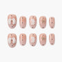Handmade press-on nails with nude pink base, white 3D bows, gold bow accents, and star details