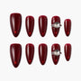 Handmade burgundy press-on nails with glossy finish and gemstone accent, arranged on white background