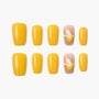 Yellow press-on nails set with two nude nails featuring 3D banana fruit design, displayed on white background.