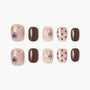 Handmade press-on nails in nude and brown with rhinestones, charms, and polka dot designs.