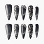 Black stiletto press-on nails with silver glitter and 3D metallic embellishments