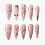 Pink press-on nails set with metallic floral, heart, and geometric embossed designs