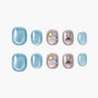 Blue and nude press-on nails set with shimmer, gem accents, and bow design