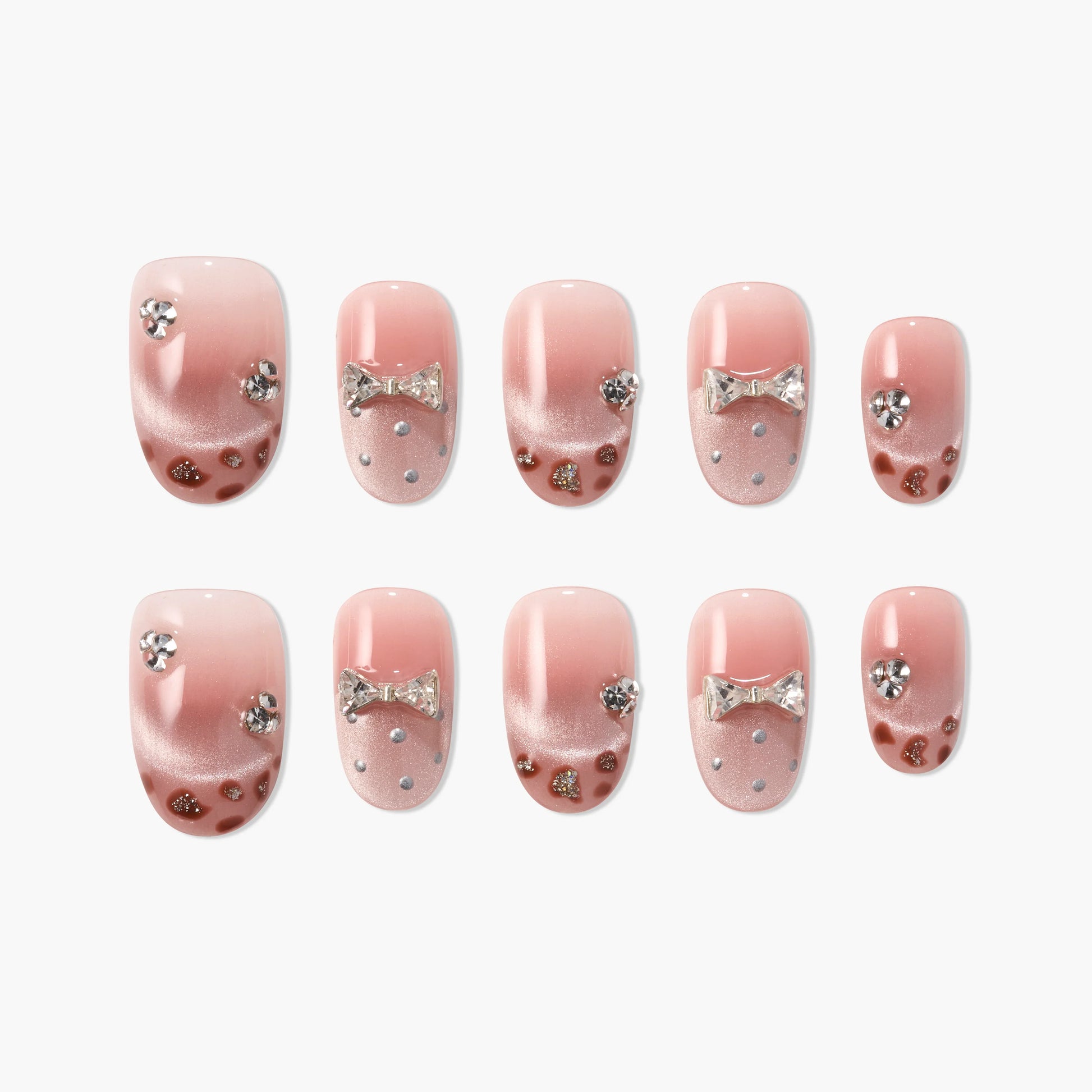 Pink ombre press-on nails with rhinestones, bows, and glitter accents, arranged in a set.