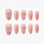 Set of pink press-on nails with 3D floral accents and glossy finish, arranged on white background.