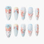 Handmade press-on nails with blue base, 3D angel, pastel roses, bows, and rhinestone accents