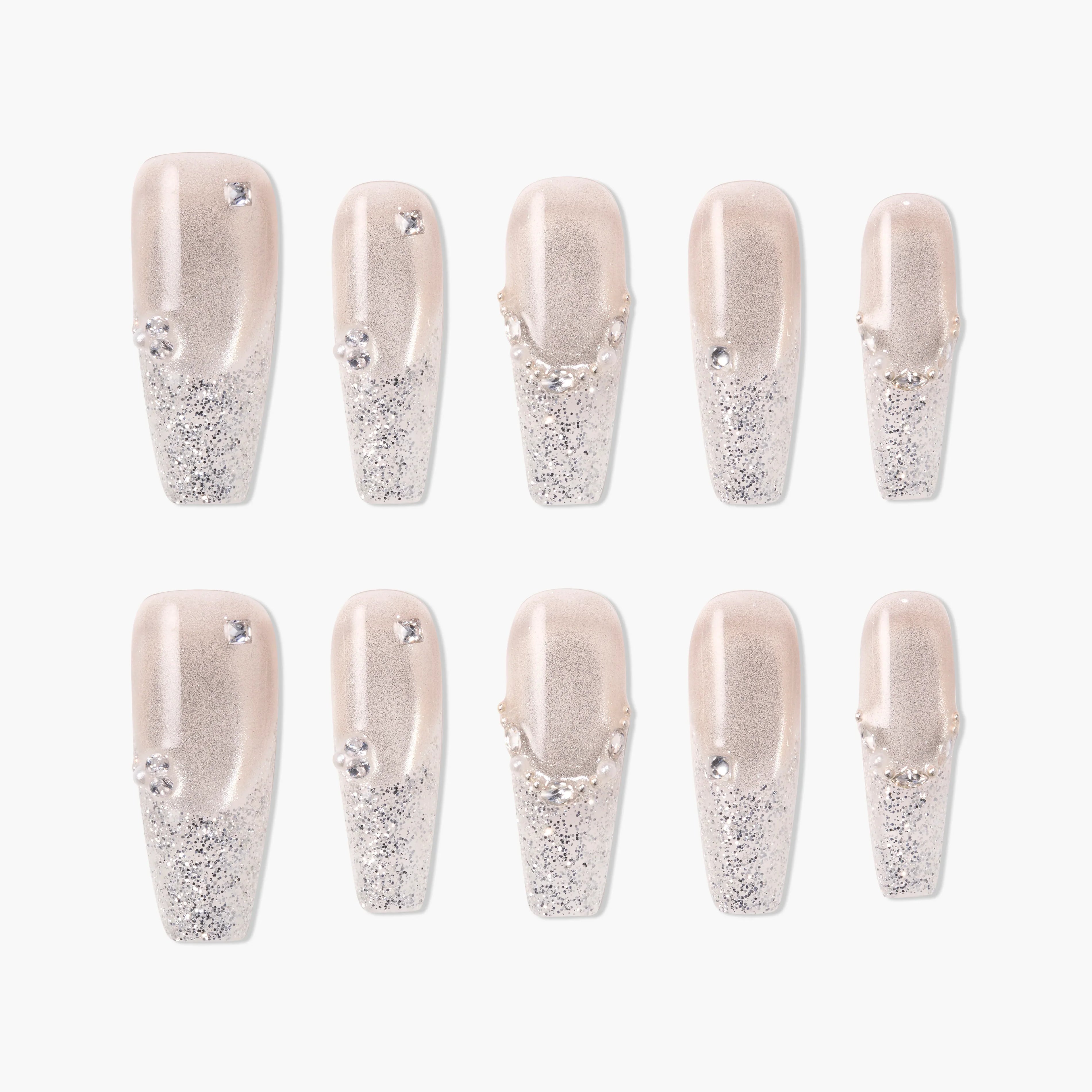 Glittery silver press-on nails with rhinestone accents and nude base, arranged in a set.