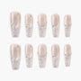 Glittery silver press-on nails with rhinestone accents and nude base, arranged in a set.