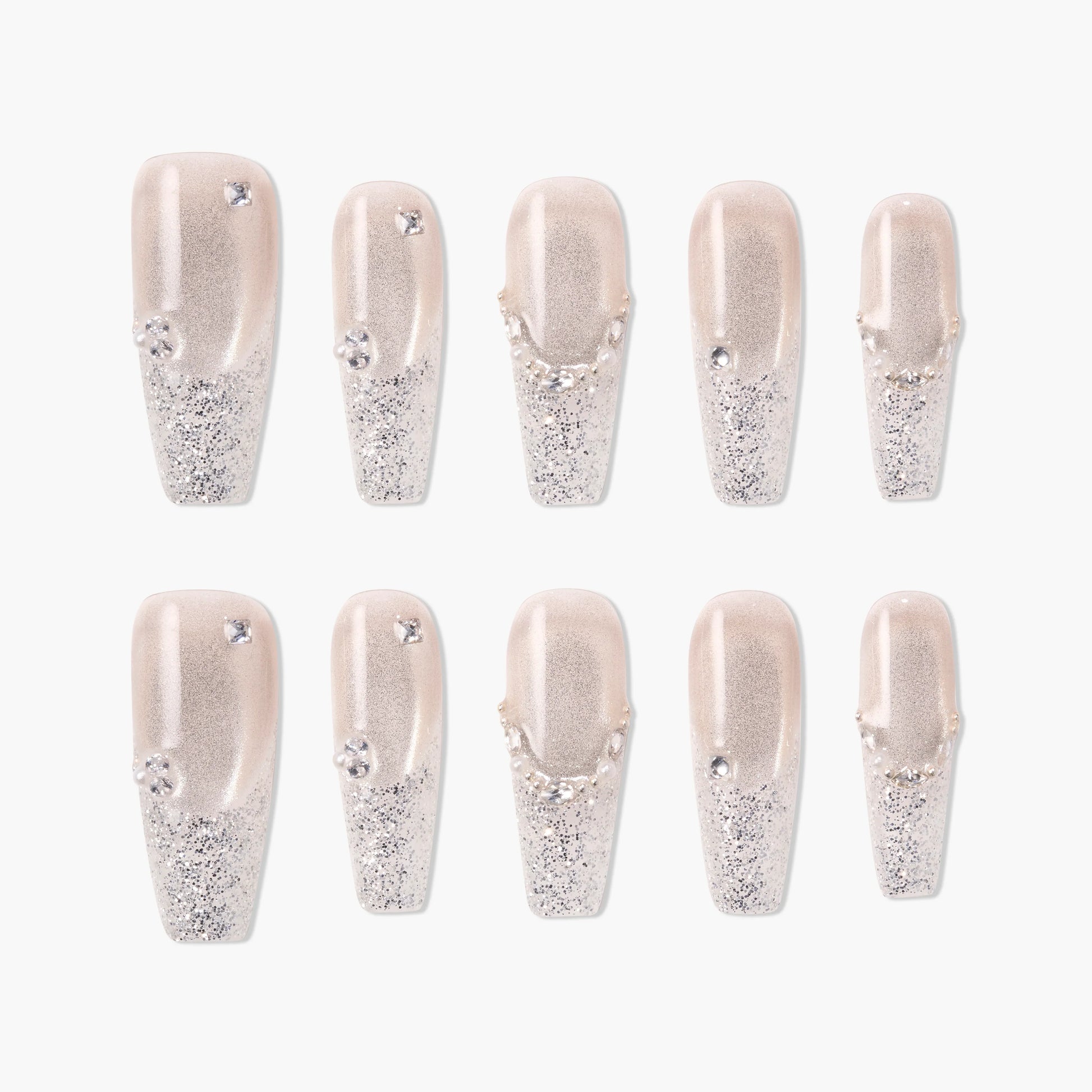Glittery silver press-on nails with rhinestone accents and nude base, arranged in a set.