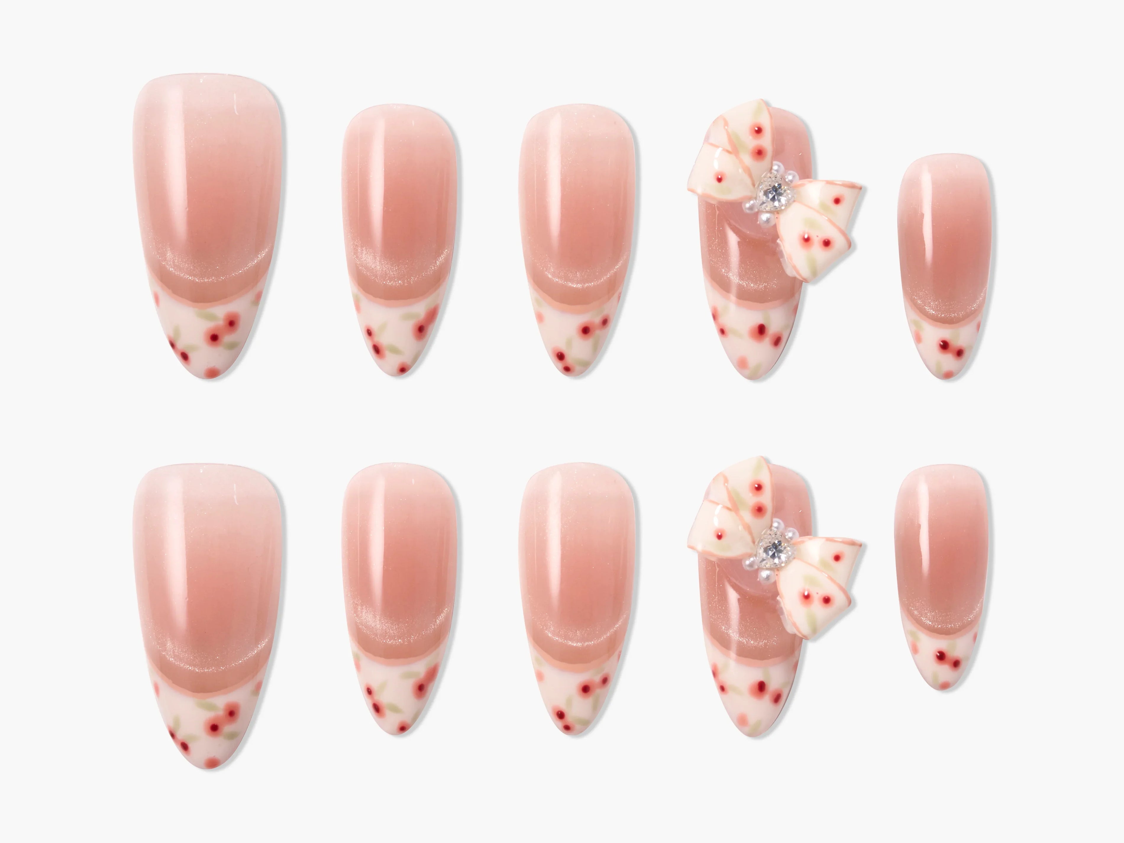 Handmade press-on nails with pink ombre, floral tips, and 3D bow accents, set on white background.