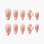 Handmade press-on nails with pink ombre, floral tips, and 3D bow accents, set on white background.