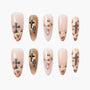 Handmade press-on nails with nude and gold tones, cross accents, and leopard print details.