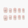 Set of blush pink press-on nails with pearl and rhinestone accents, arranged on white background.